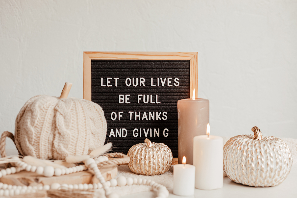 White and beige candles and felt pumpkins with letter board expressing thanks and grace