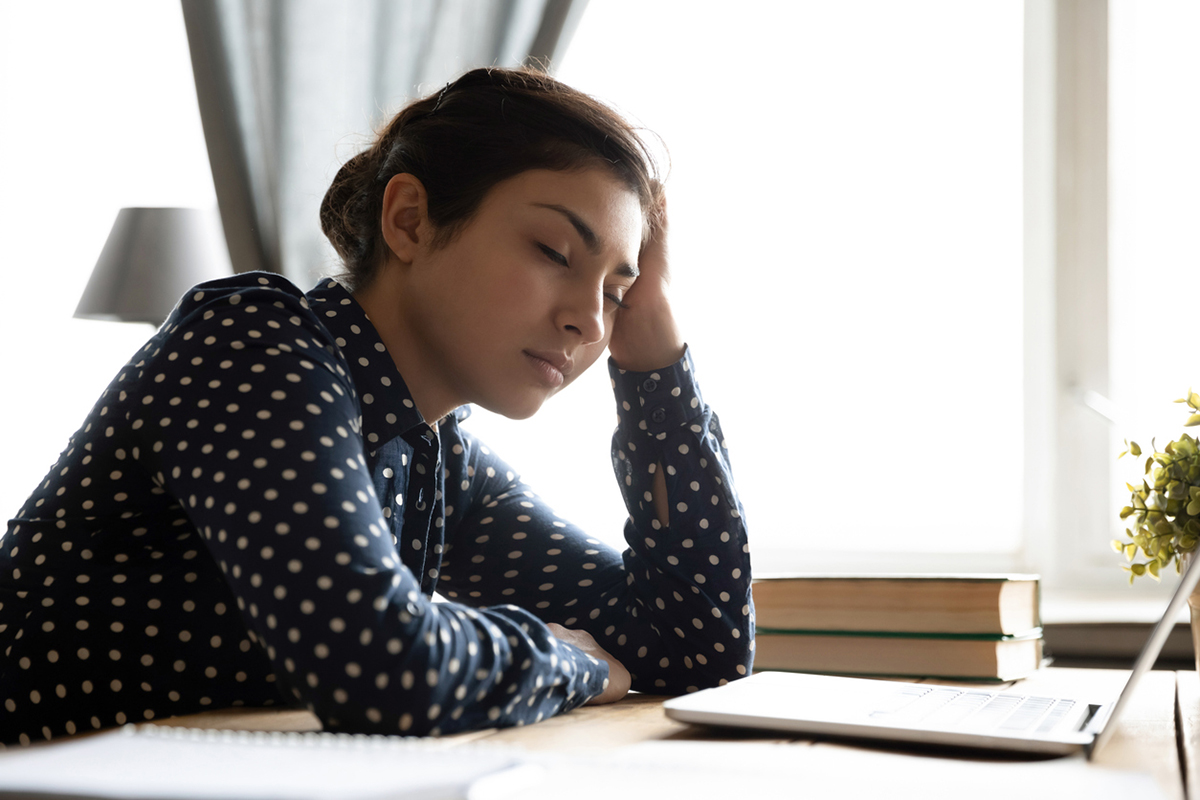 young woman bored with the thought leadership content she is reading on her laptop