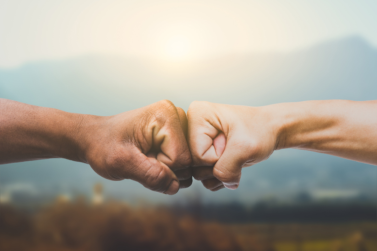 Dark skinned hand and light skinned hand doing a fist bump