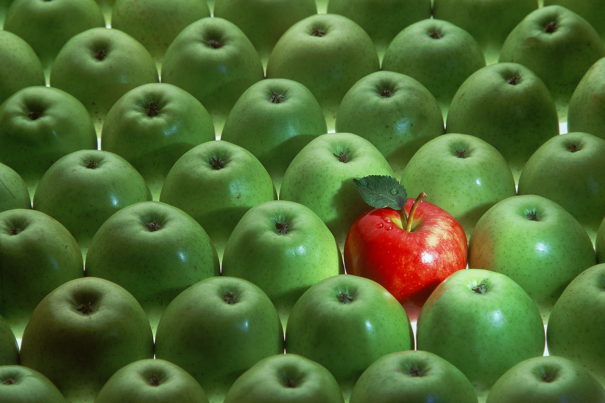 1 red apple toward the middle of a bunch of green apples