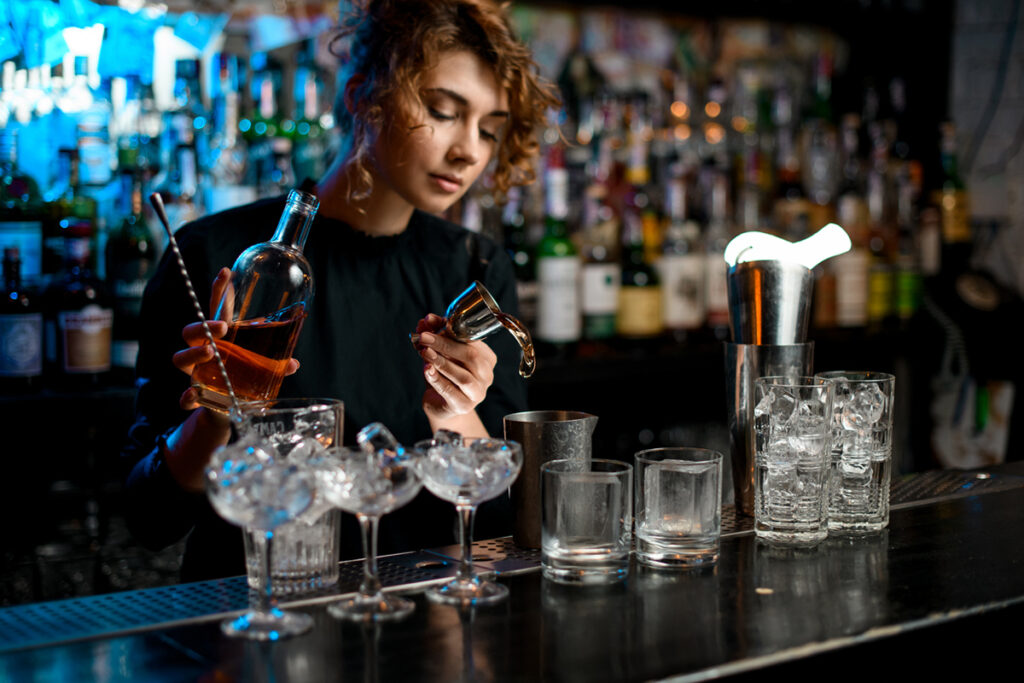 Busy female bartender mixing drinks