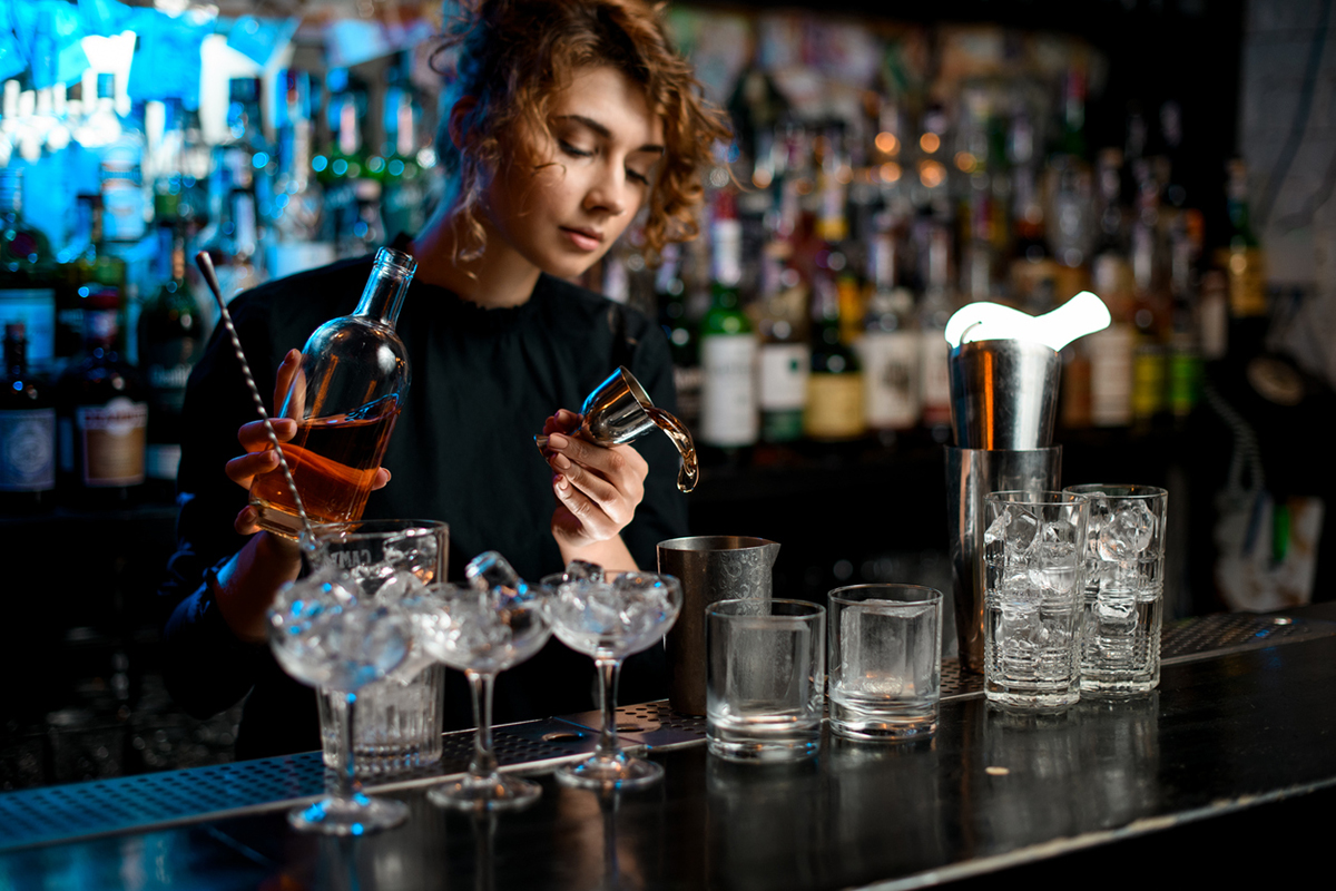 Busy female bartender mixing drinks