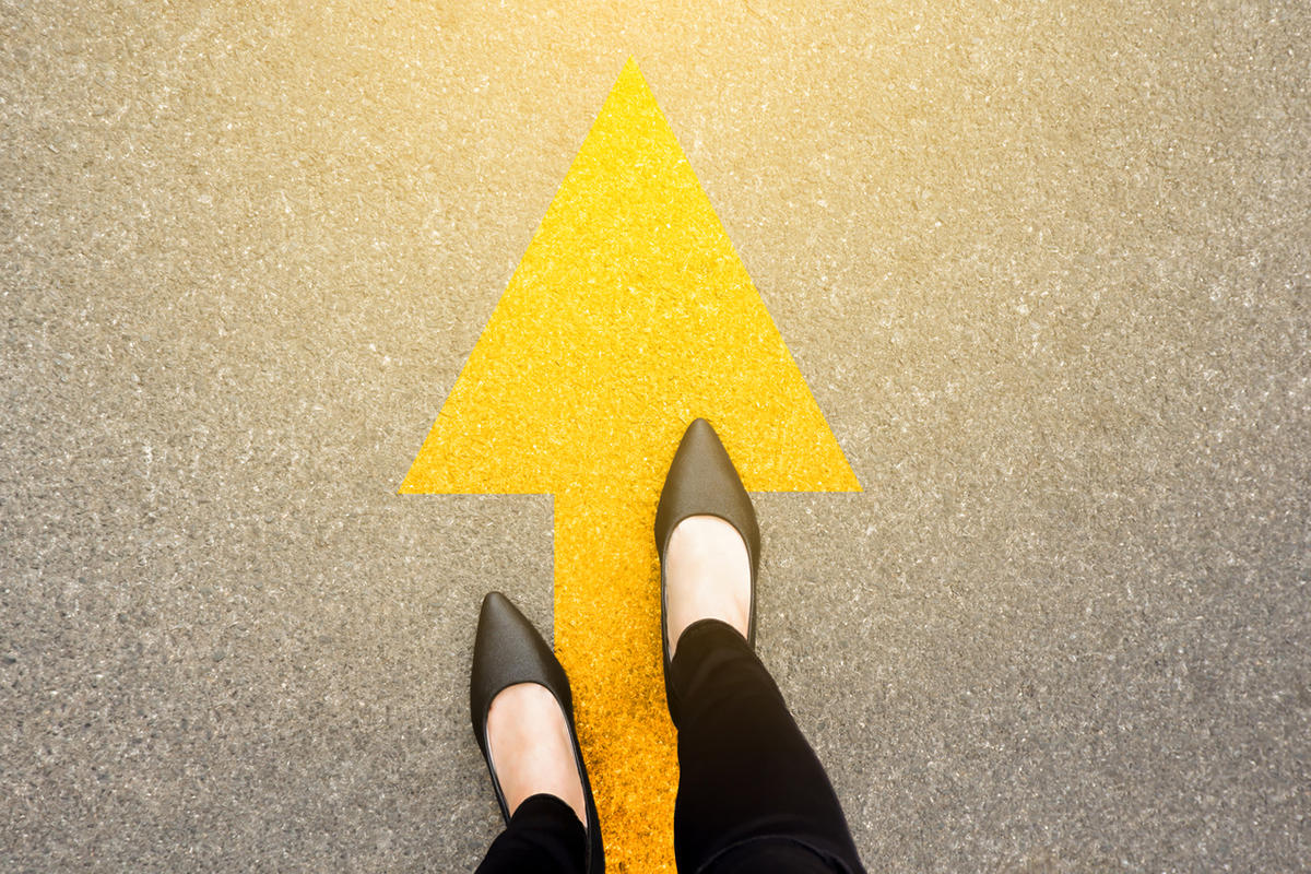 Yellow arrow on the ground with a woman's feet on it
