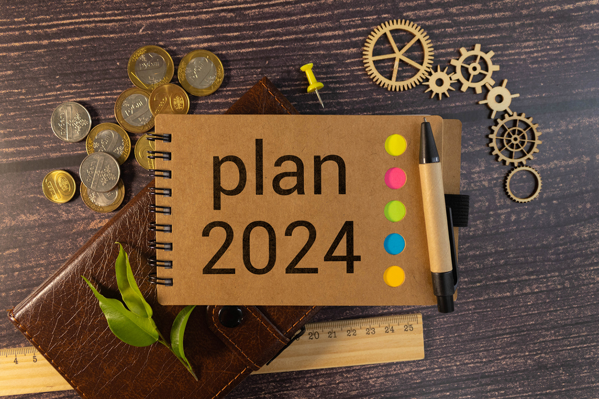 Content marketing illustration -- Notebook with the words Plan 2024 on them, surrounded by coins, gears and a ruler