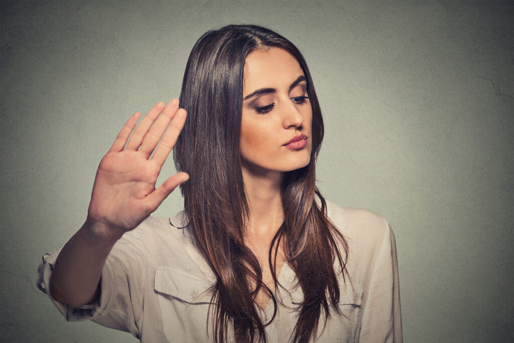 Young white woman with long dark hair holding up her hand rejecting ideas