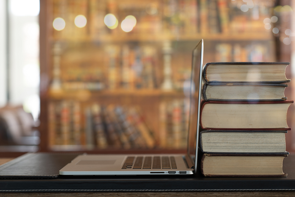 Business books stacked next to a laptop