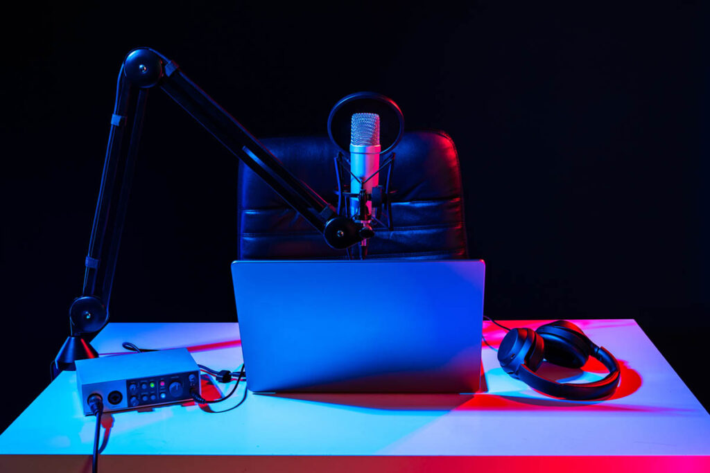 Microphone, laptop, headphones on a desk with neon light shining, illustrating a brand strategy lessons from evolving from rapping to podcasting.