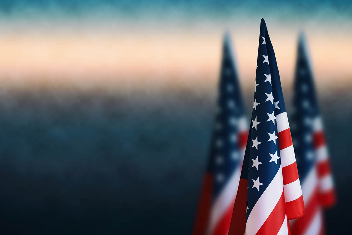 American flags against a blue fog background, representing July 4 and the question, is America still free?