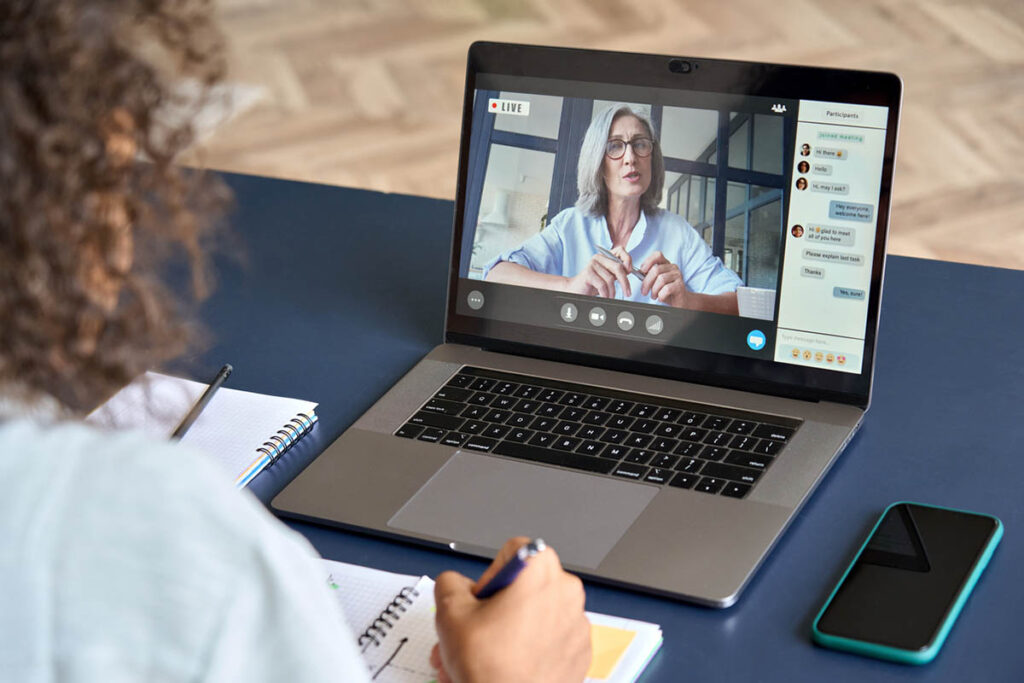 Person watching a live webinar presented by an older woman and showing high engagement, illustrating the high webinar engagement stats researchers are seeing.