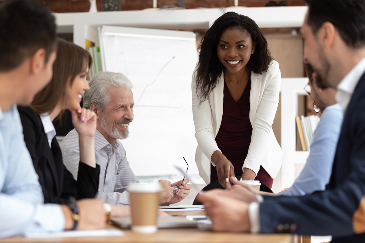 Smiling young black woman leading a team meeting, representing confidence, trust, and credibility built through thought leadership in sales.