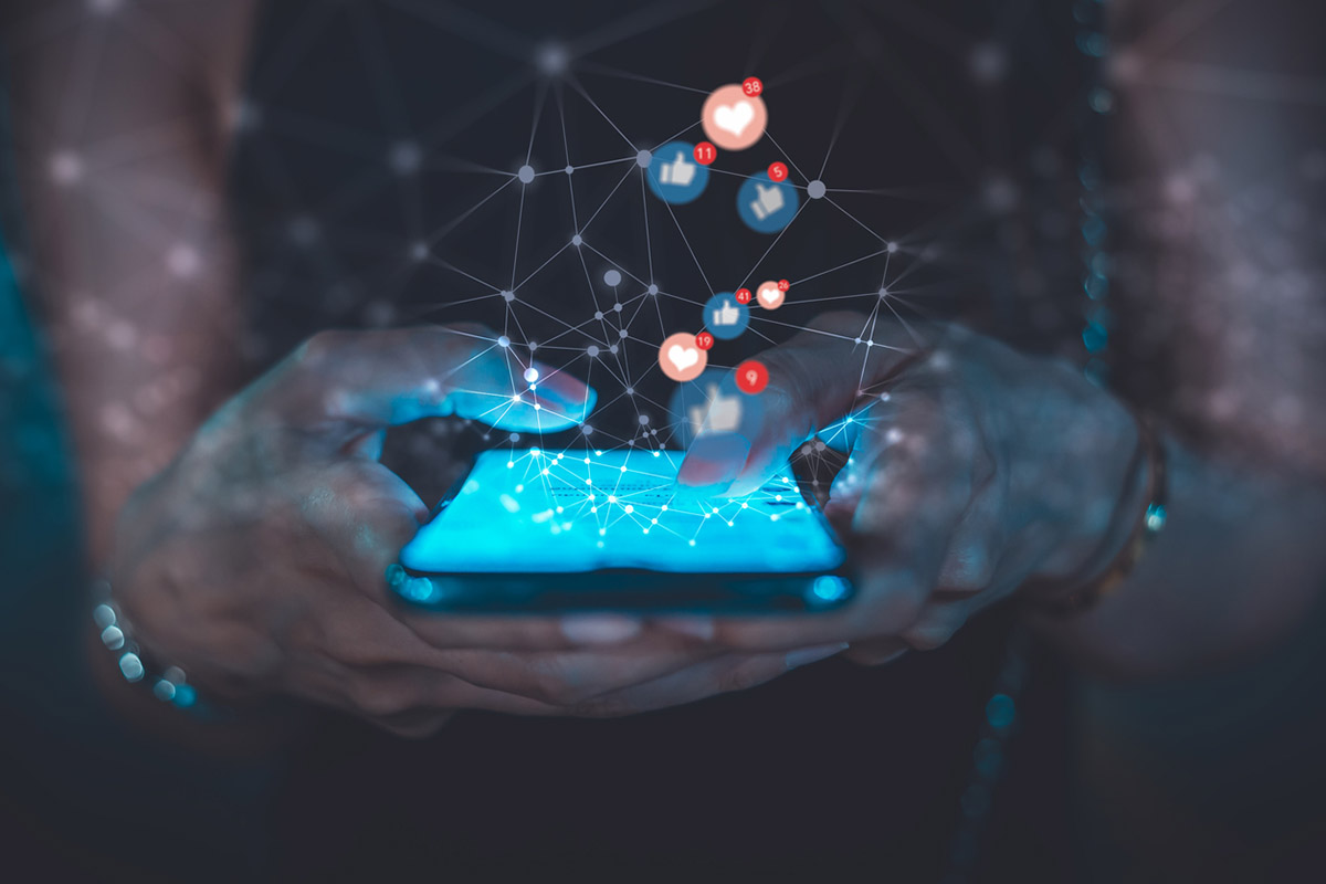 Close-up of hands using a smartphone with floating social media like and heart icons, representing engagement and declining trust in influencer marketing.