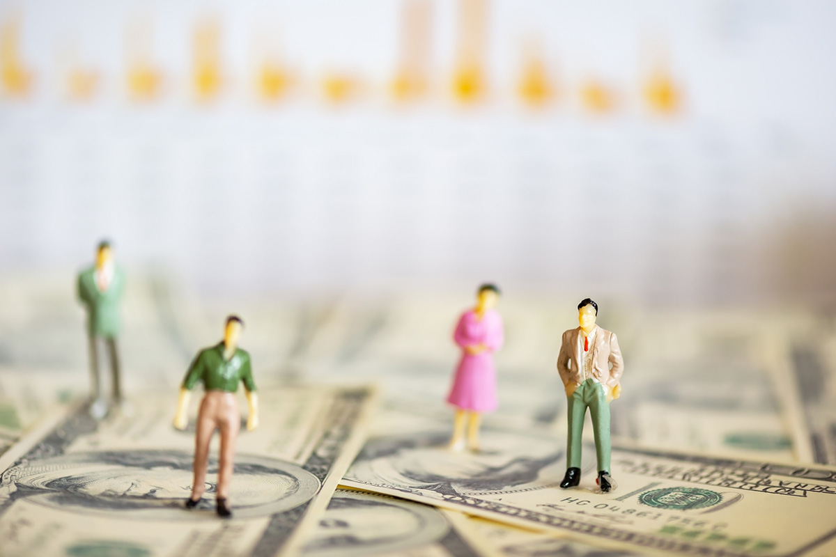 Miniature businesspeople standing on a pile of dollar bills, symbolizing the complexity and financial stakes of B2B buying decisions within buyer groups.