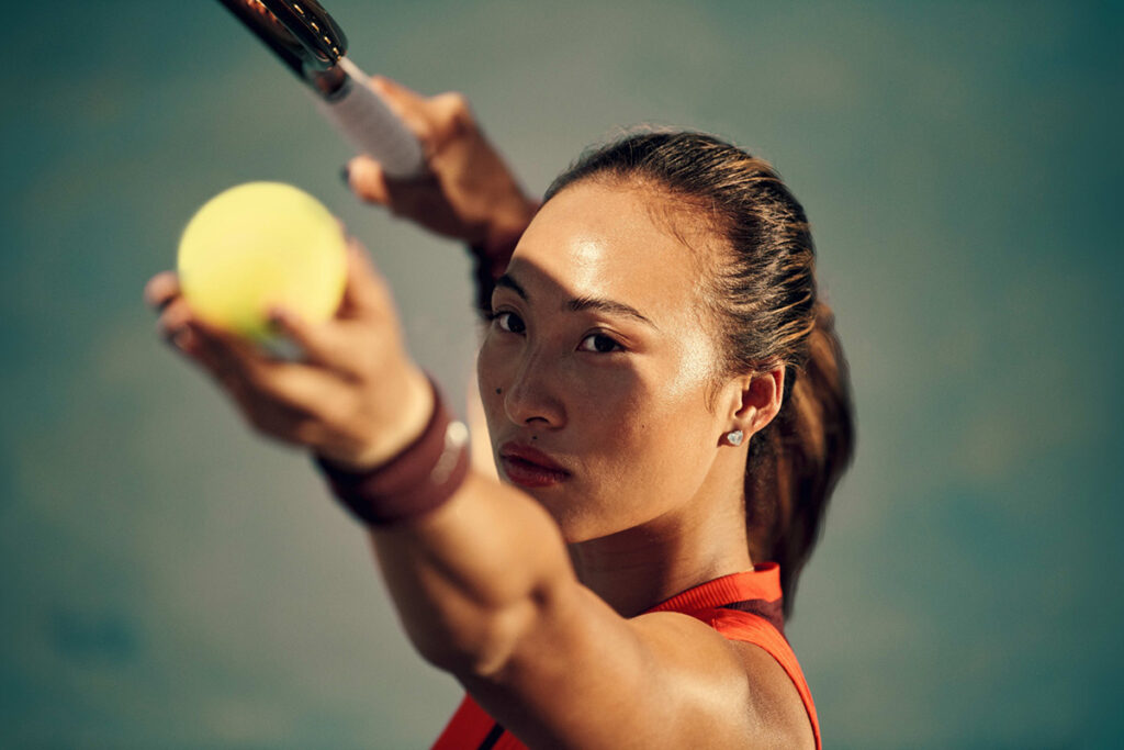 Close-up of professional tennis player Qinwen Zheng preparing to serve, featured in Nike’s “Why Do It?” campaign, illustrating the brand evolution behind the updated slogan.