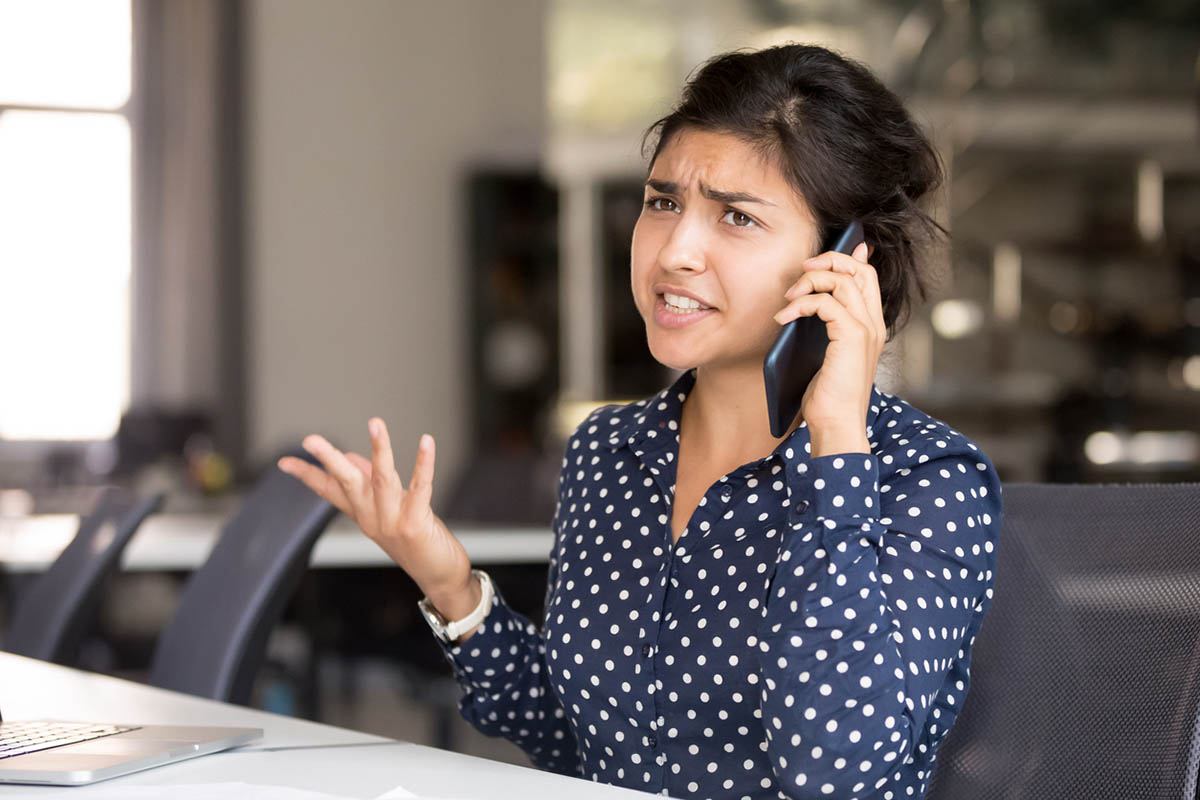 Woman on the phone at a desk, looking frustrated while addressing a customer service issue, illustrating how unresolved problems impact the customer experience.
