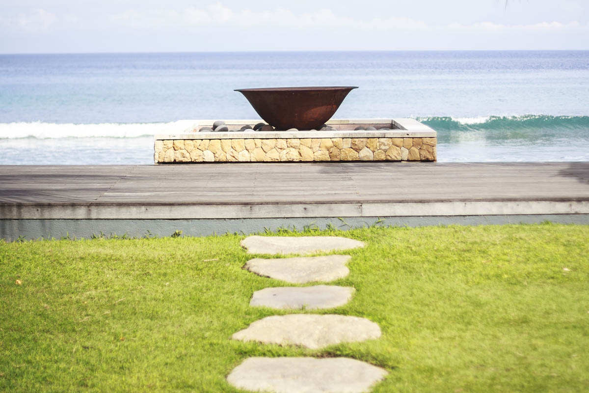 Stepping stones forming a path across grass toward the ocean, representing overcoming fear in business one step at a time.