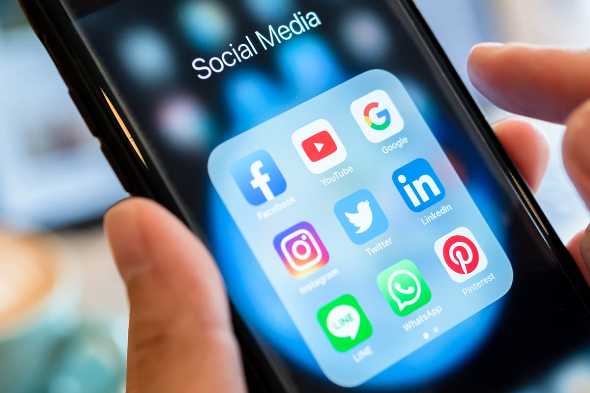 Hand holding a smartphone with social media apps visible on the screen, illustrating changing trends in what works on LinkedIn and how users engage with content.