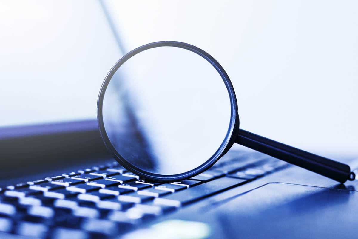 Close-up of a magnifying glass resting on a laptop keyboard, symbolizing search analysis and discovery, representing an intent-first SEO strategy focused on understanding user intent beyond keywords.