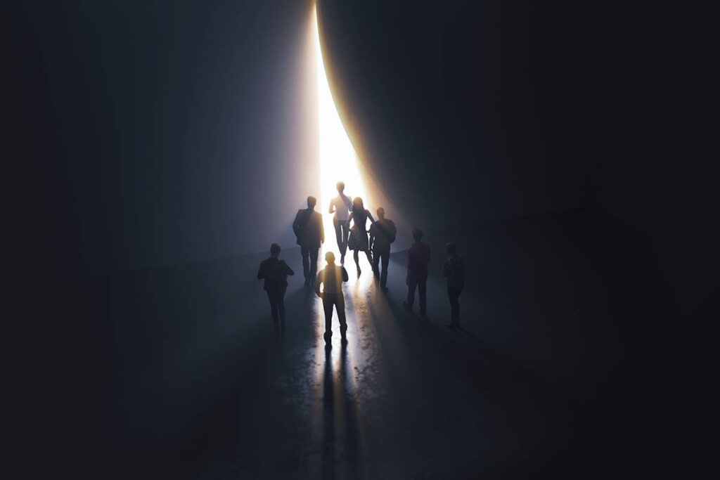 Silhouettes of people walking toward a bright opening in a dark space, symbolizing guidance, trust, and thought leadership credibility during uncertain times.
