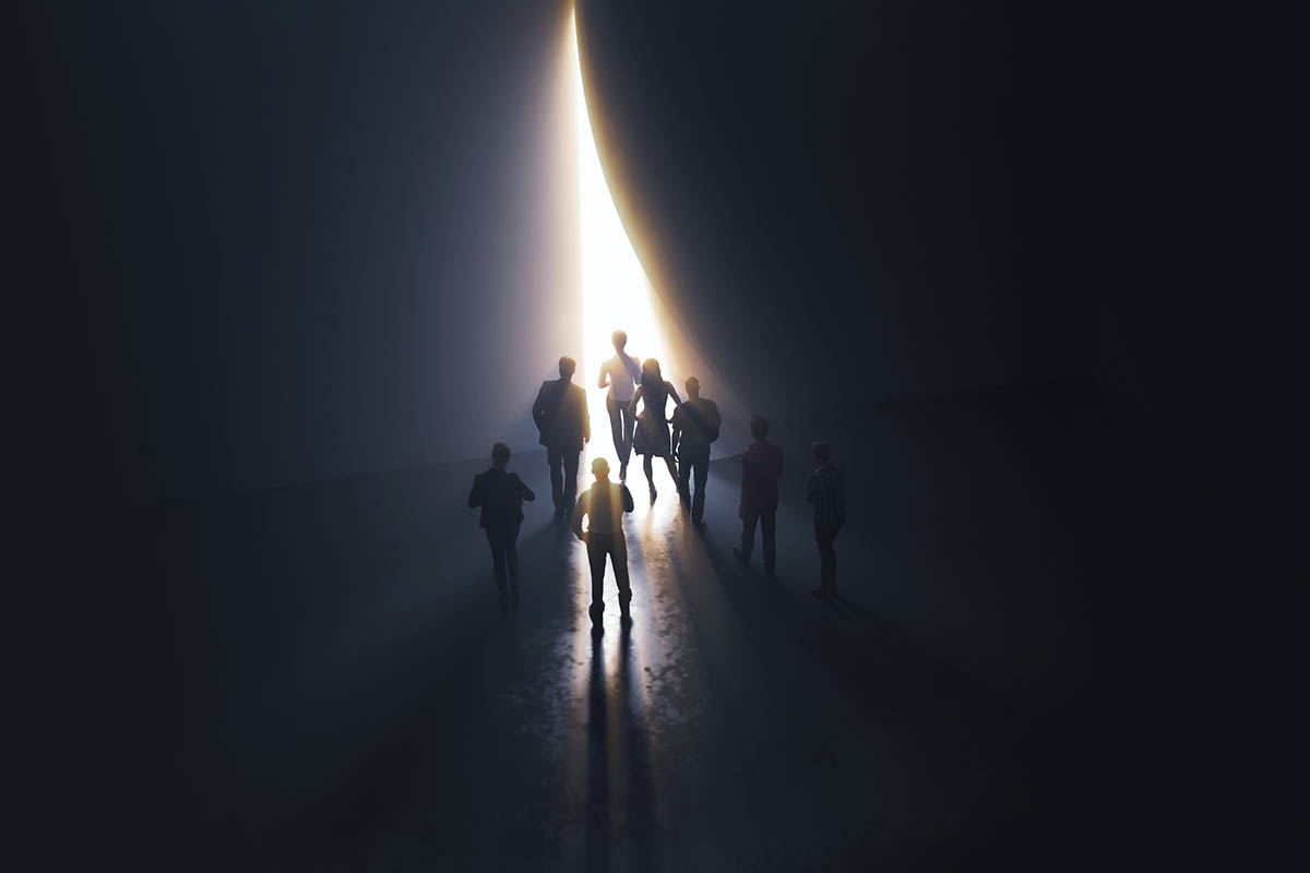 Silhouettes of people walking toward a bright opening in a dark space, symbolizing guidance, trust, and thought leadership credibility during uncertain times.