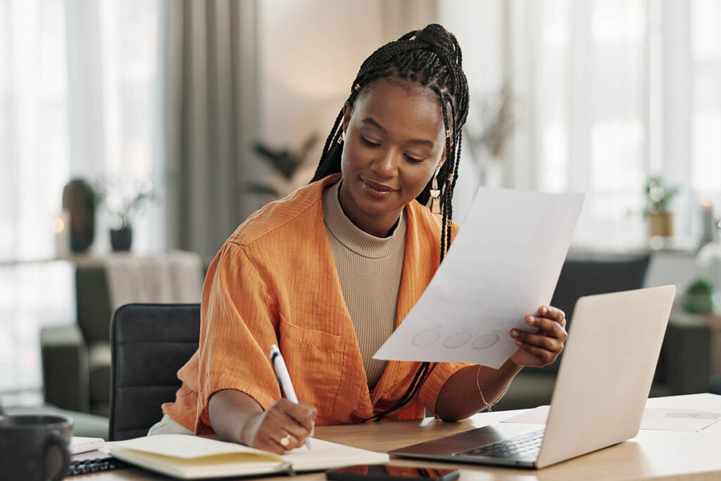 A professional reviews documents and research findings while working at a laptop, illustrating how B2B buyer trust is built through careful evaluation, credible sources, and pre-purchase research.