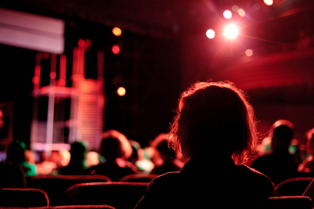 An audience watches a live theater performance from their seats, illustrating how context influences market perception and shapes the expectations people bring before an experience even begins.