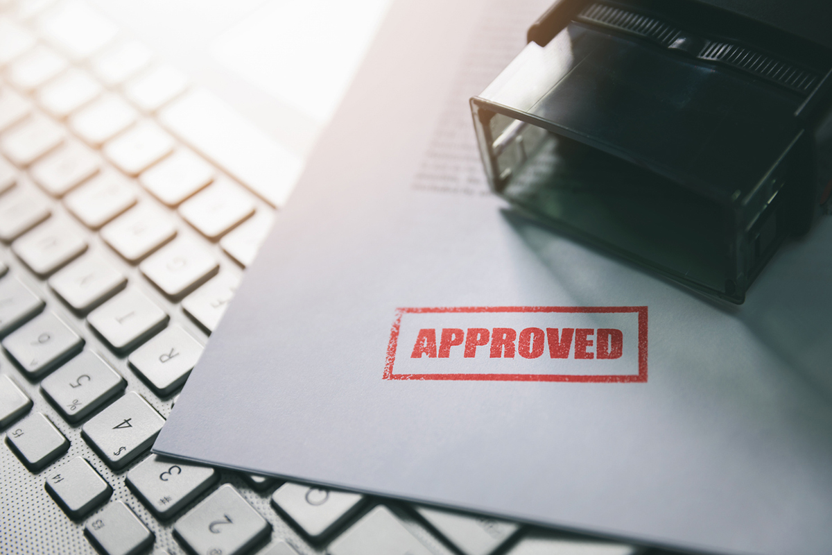Business document with an "Approved" stamp next to a keyboard and rubber stamp, representing strategies to justify investments to decision-makers.