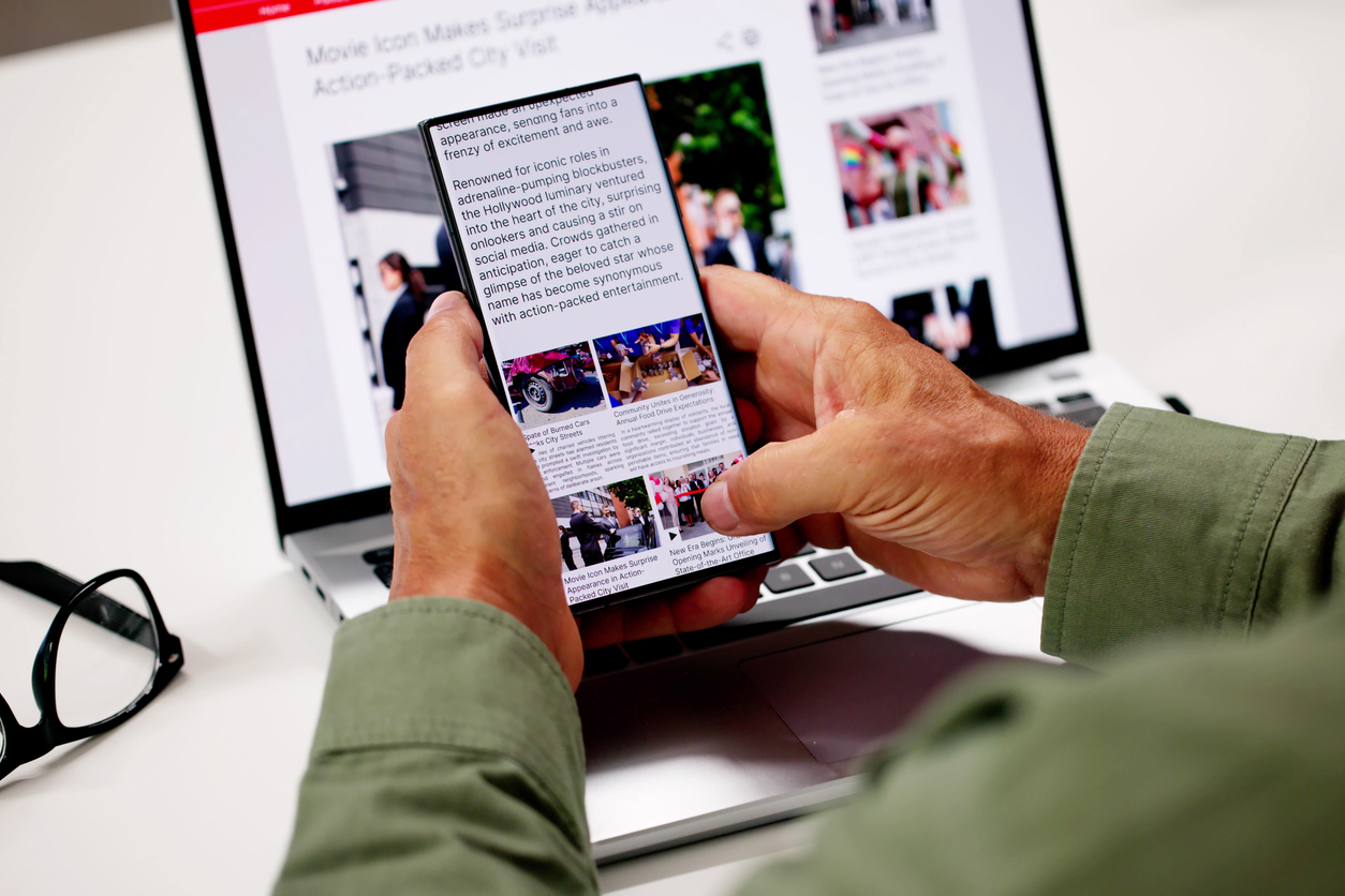 Watching Online News Article On Mobile Phone And Laptop. Electronic Newspaper